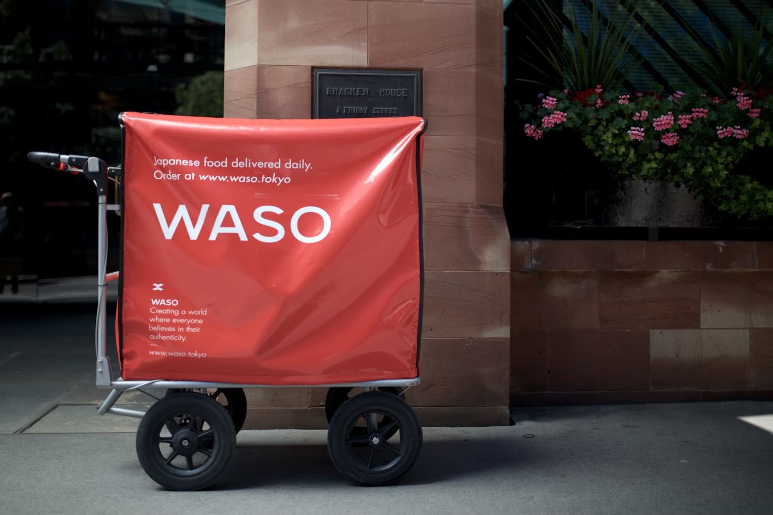 Red delivery trolley parked in front of Bracken House in London